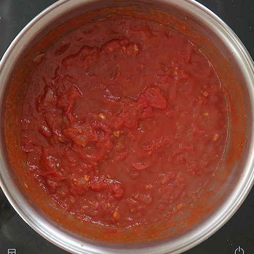 Domowy sos marinara gotujący się na wolnym ogniu w garnku.