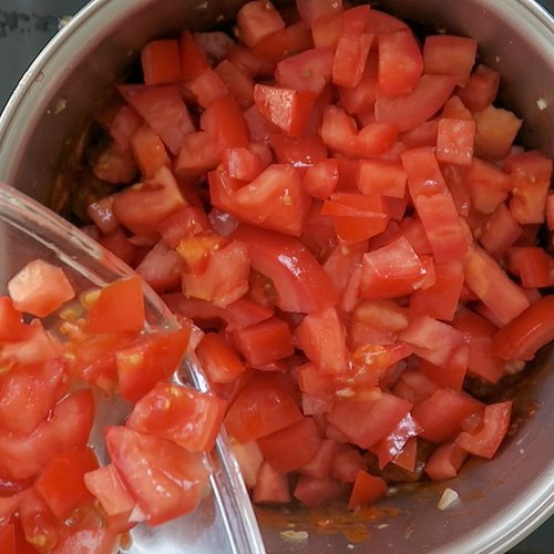 Składniki na domowy sos marinara: świeże pomidory, czosnek, cebula i oliwa z oliwek na drewnianym blacie.